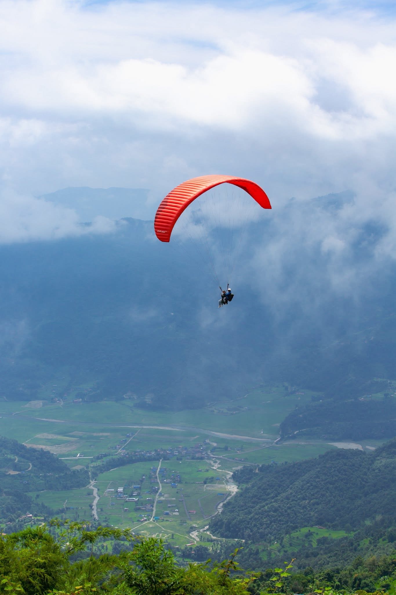 Paraglider flying through clouds above Pokhara